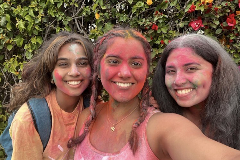 Three students celebrating the Holi Festival.