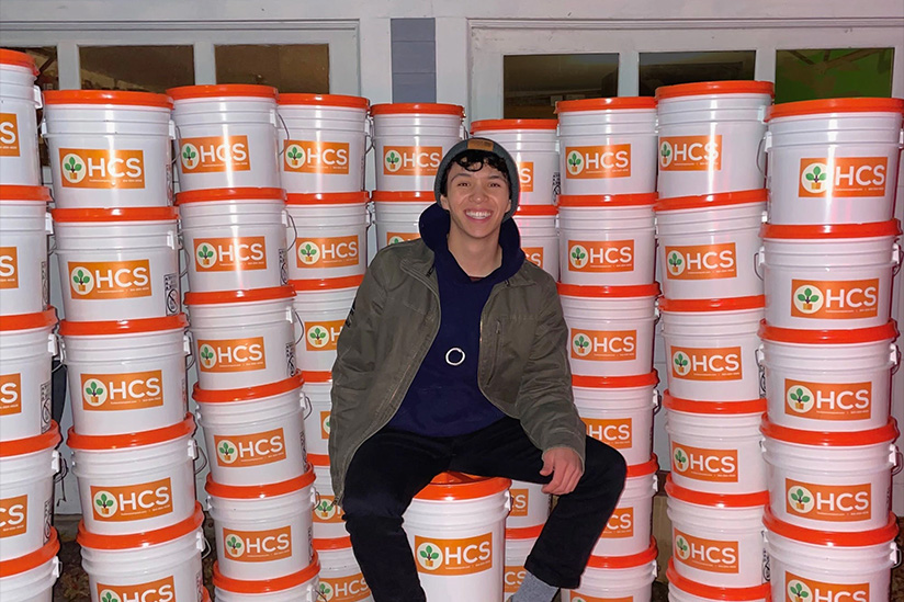 USC IYA student, Ben Wan in front of composting buckets
