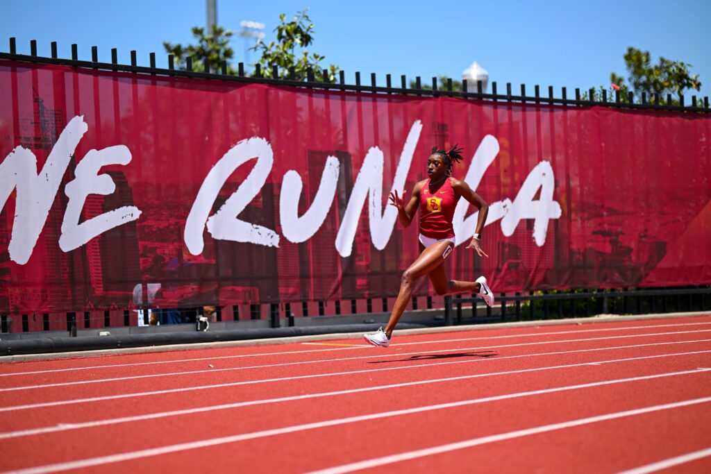 A USC Track and Field runner zooms past a We Run L.A. sign in Allyson Felix Field