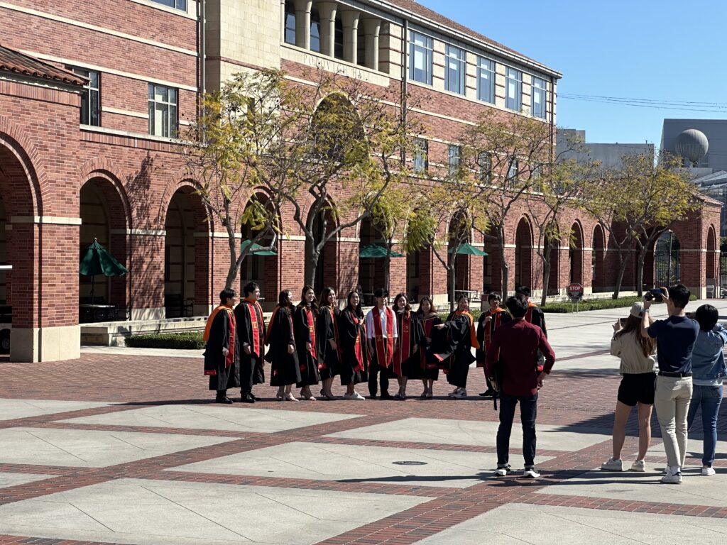 A group of graduating seniors ready to take a group photo in front of Popovich Hall