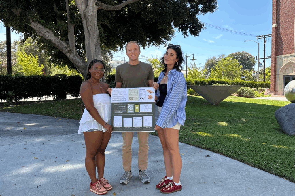 Three USC students standing outside in front of a tree holding Architecture design